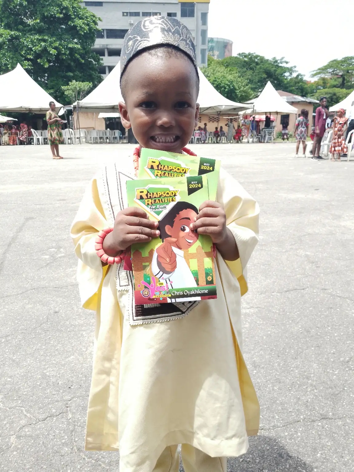 A smiling child holding Rhapsody of Realities during an outreach celebration.